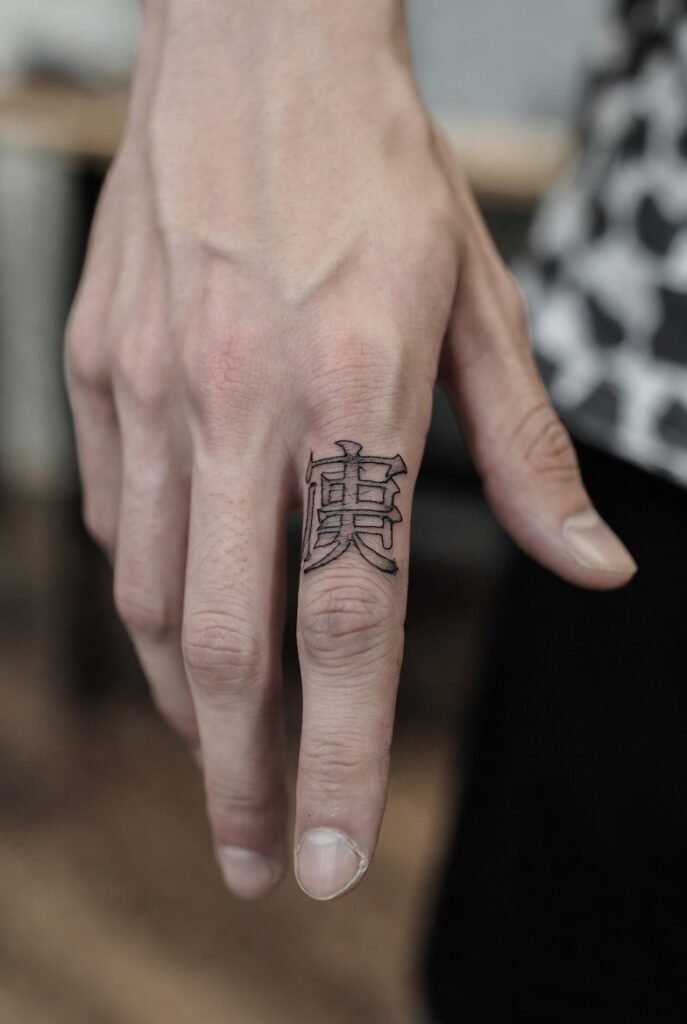A portrait-style shot of a Japanese hand featuring a triggerfinger tattoo, the tattoo rendered in razor-sharp detail.