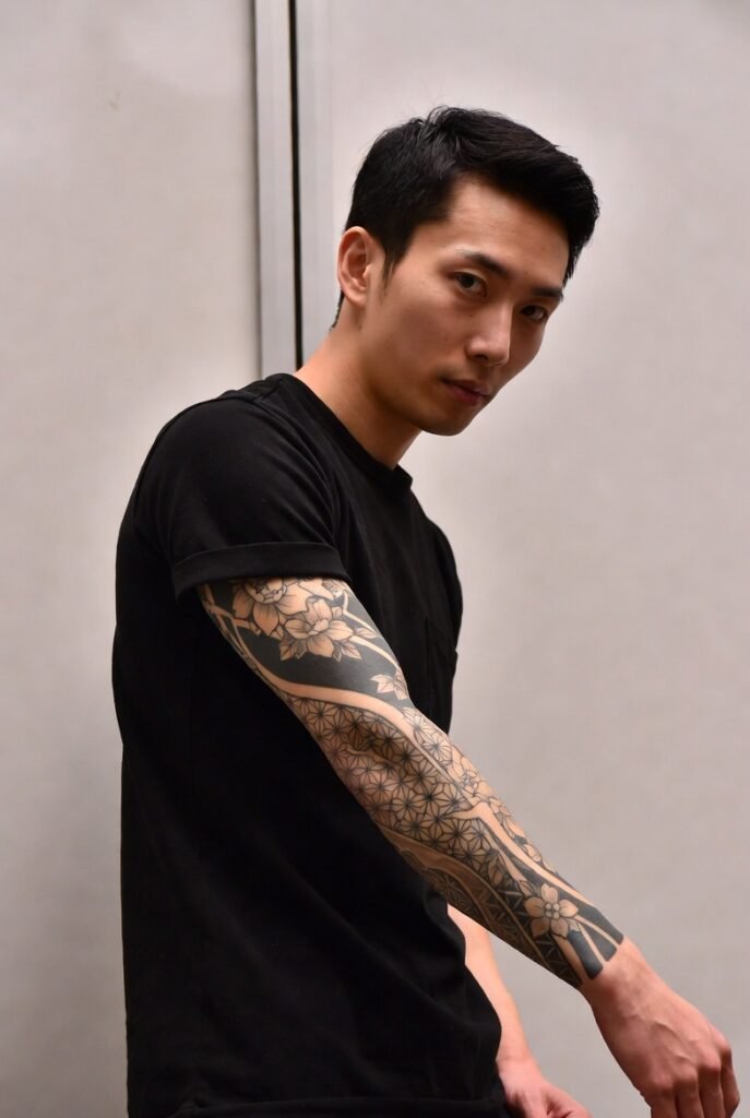 20+ Japanese Tattoos for Men: Discover the Bold and Intricate Designs 2026 10 A Japanese man in a casual t-shirt, photographed with emphasis on his arm tattoo.