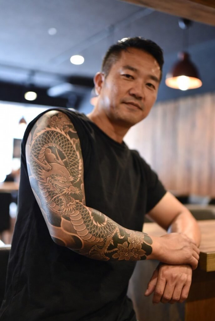 20+ Japanese Tattoos for Men: Discover the Bold and Intricate Designs 2026 15 A portrait-style shot of a Japanese man in a t-shirt, emphasizing the arm tattoo.