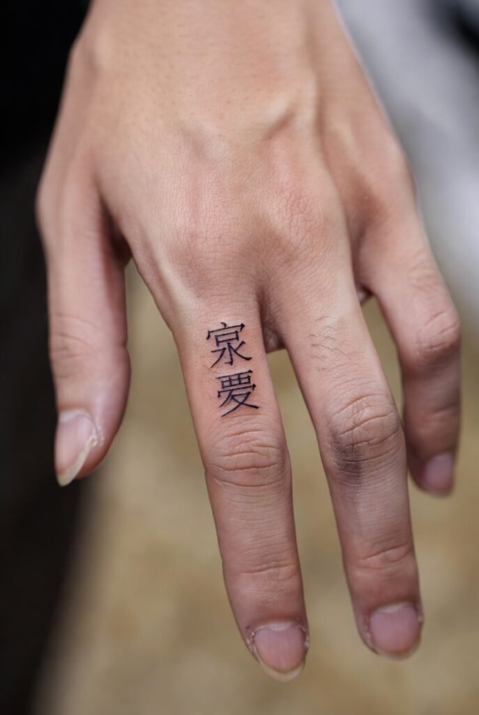 A photo of a Japanese hand marked by a triggerfinger tattoo, with the ink as the primary focus.