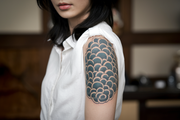 A Japanese woman with a detailed cloud tattoo, her face clearly visible in the frame.