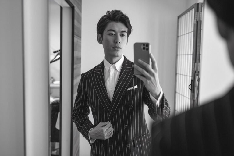 Japanese man taking a mirror selfie wearing a premium tailored designer jacket with clean lines and luxurious material — tokyo mens designer fashion.